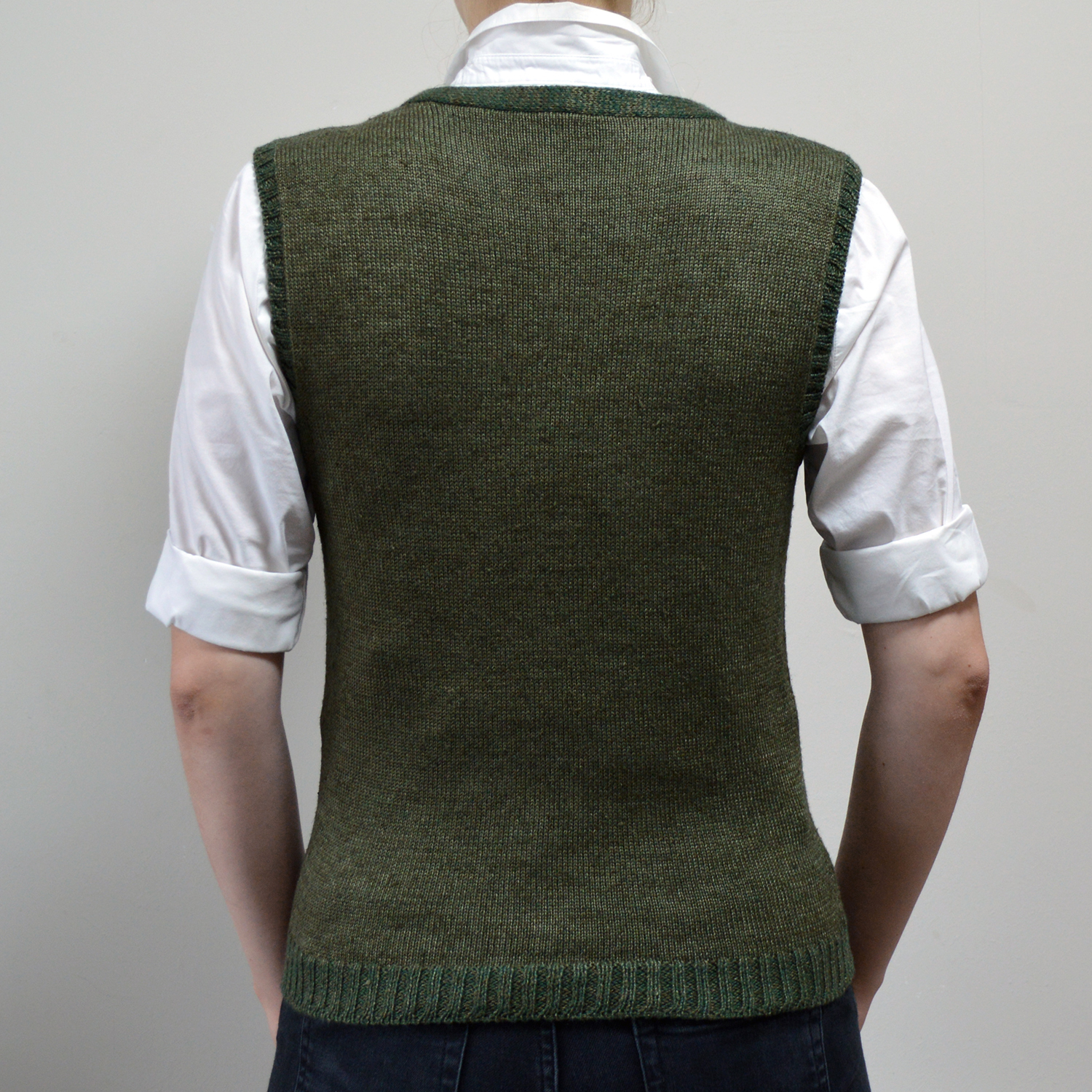 Handknitted green vest by INESKA — back view with white shirt