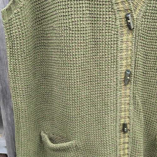 Hand-crocheted openwork pocket and buttons on an olive green knitted vest