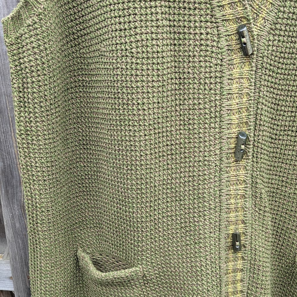 Hand-crocheted openwork pocket and buttons on an olive green knitted vest