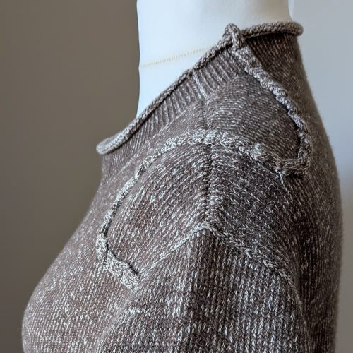 Handgebreide winterjurk detail, schouder met vlecht en labyrintlijnen, wol en katoen, handgemaakt in Nederland