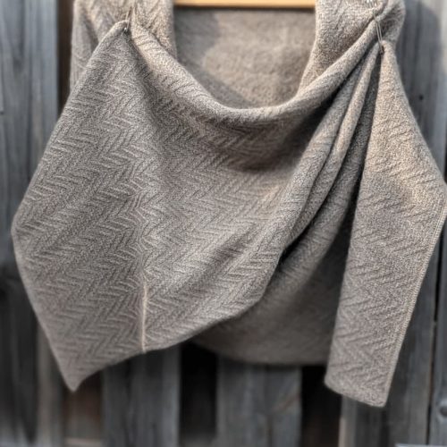 Hand-knitted mohair merino cashmere scarf in taupe with herringbone texture and two decorative pins, draped on a wooden hanger