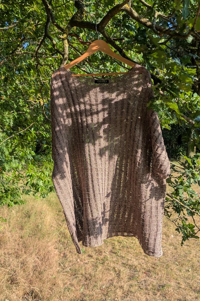 Hemp knit tunic on a wooden hanger in a tree, dappled sunlight through green leaves, INESKA Creative Atelier