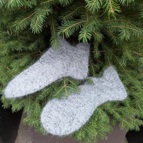 Grey fluffy hand knitted merino and mohair sleeping socks resting on fir branches